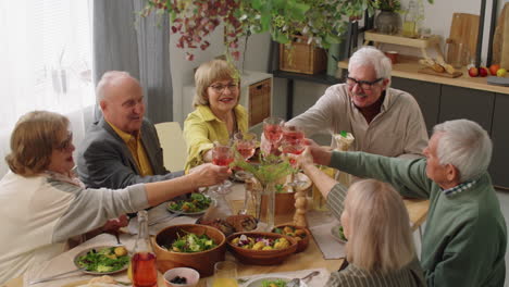 Ältere-Freunde-Stoßen-Beim-Abendessen-Zu-Hause-Toast-An